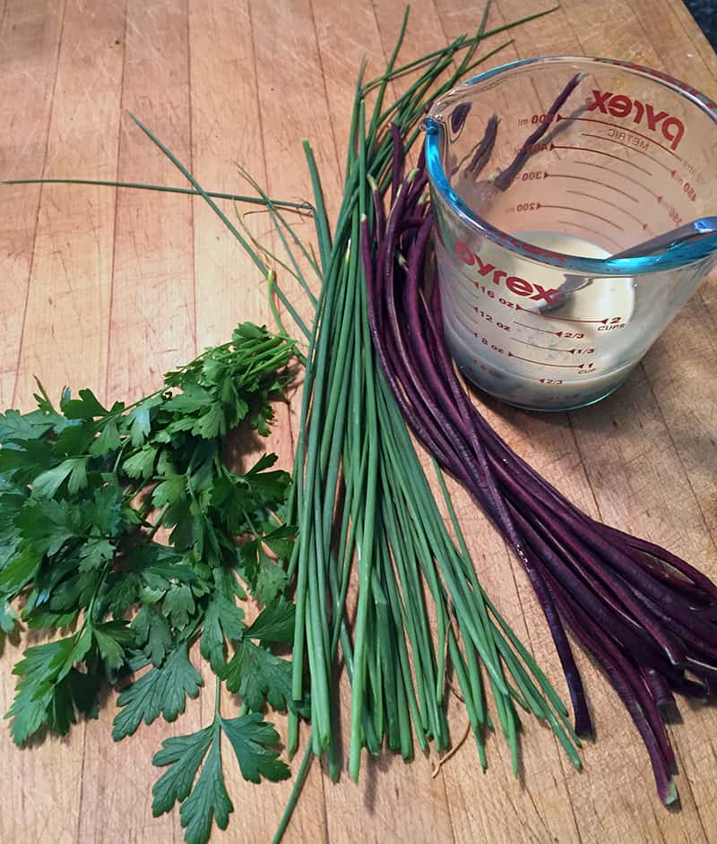 chives on a cutting board with red noodle beans and cilantro, ready to make into a stir-fry