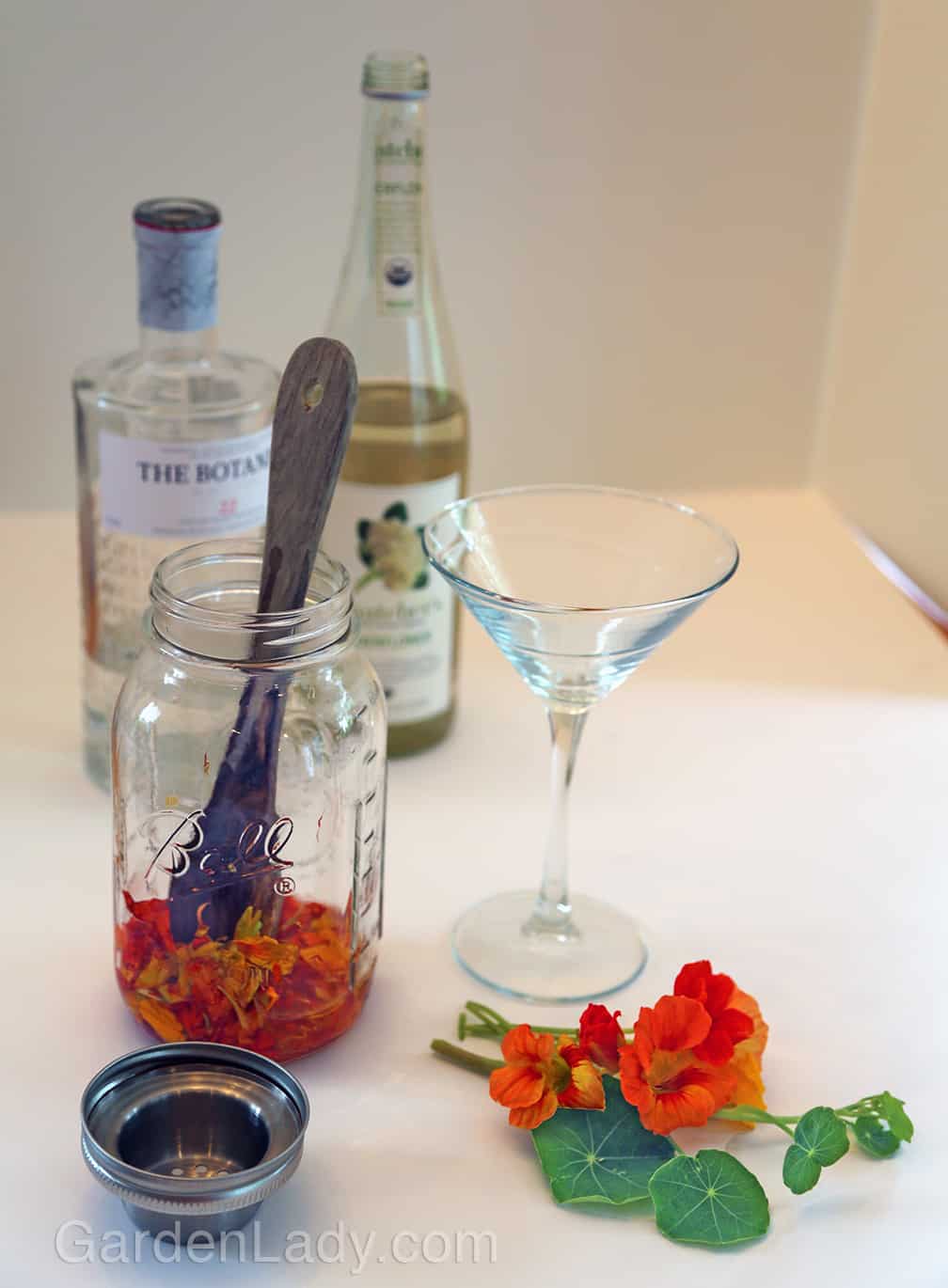 Muddle the flowers by smashing them with a wooden spoon, then add the liquids.